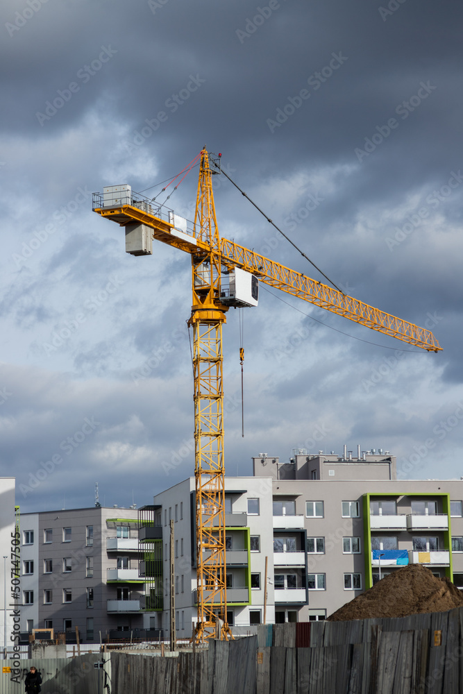 Yellow construction jib crane tower against blue sky on the construction site