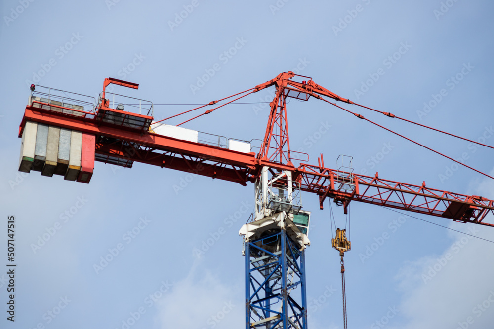 Modern red construction cranes above blue sky