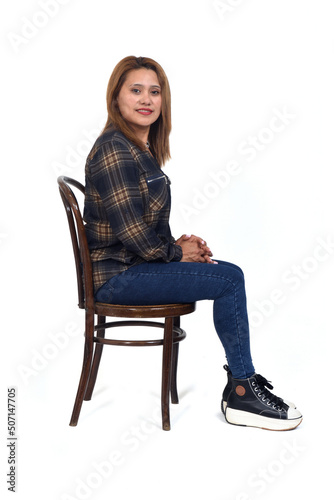side view of a woman sitting on chair looking at camera on white background