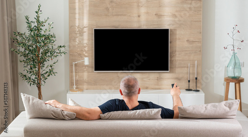 man in modern living room watching tv back view