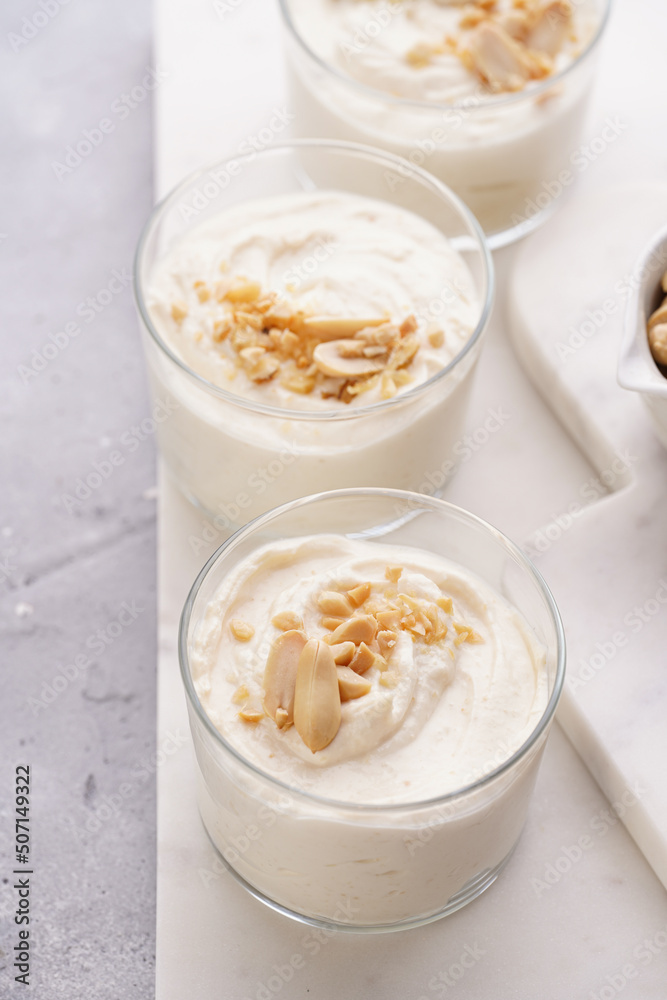 Creamy dairy yoghurt dessert with mascarpone, cream cheese and peanut butter in glasses on marble tray Creamy dairy yoghurt dessert with mascarpone, cream cheese and peanut butter in glasses on marble tray
