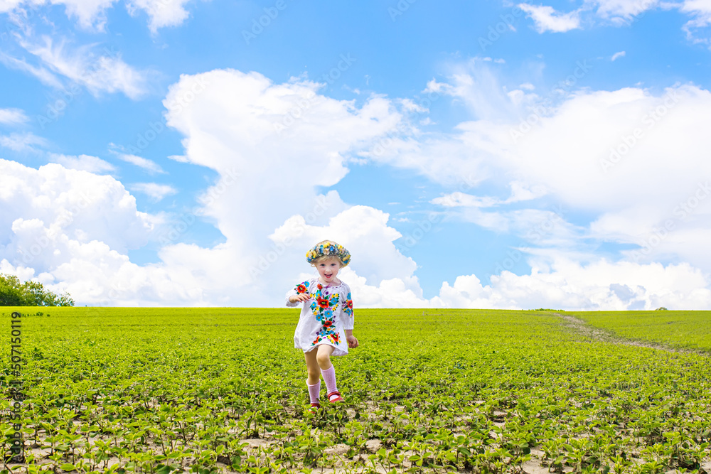Happy Ukrainian child in free Ukraine without war runs along a rural road in a field of farm soybean. Constitution Day or Independence Day Happy Ukrainian child in free Ukraine without war runs along a rural road in a field of farm soybean. Constitution Day or Independence Day
