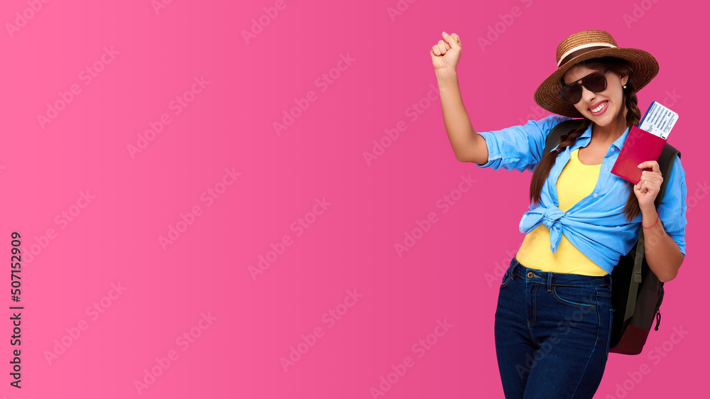 Amazed and smiling woman traveler in straw hat and sunglasses holding plane ticket and passport on pink isolated background Amazed and smiling woman traveler in straw hat and sunglasses holding plane ticket and passport on pink isolated background