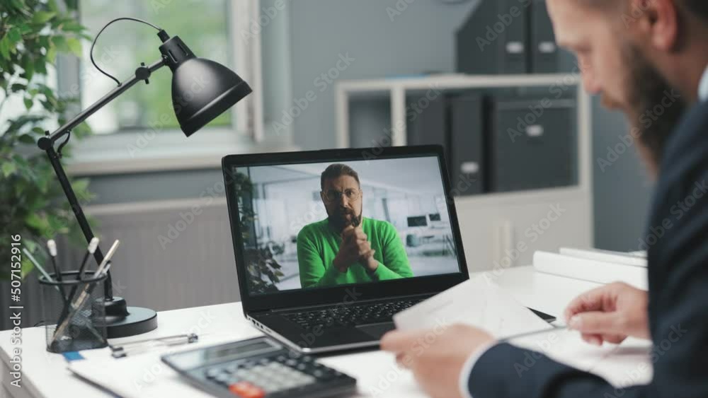 Over shoulder view of successful businessman sitting at workplace and using modern laptop for video conference with male colleagues. Concept of people, technology and online communication. Over shoulder view of successful businessman sitting at workplace and using modern laptop for video conference with male colleagues. Concept of people, technology and online communication.