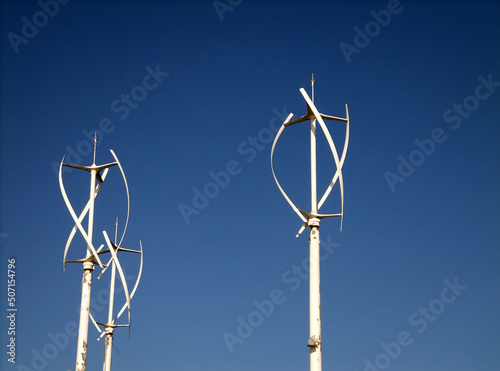 a group of small vertical wind turbines against a blue sky