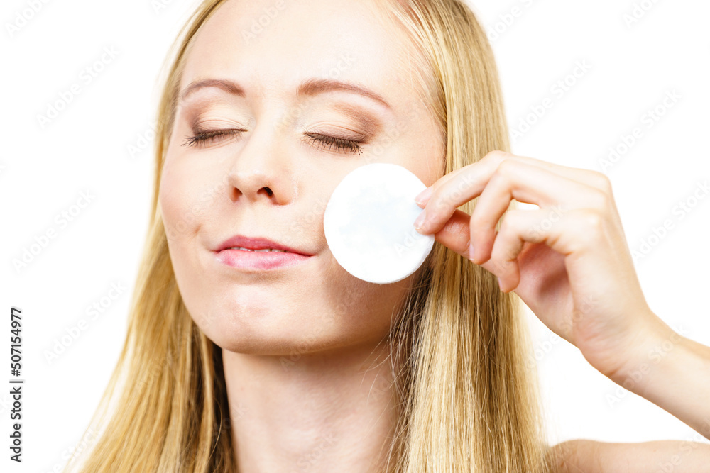 Woman cleaning her face skin with cotton pad