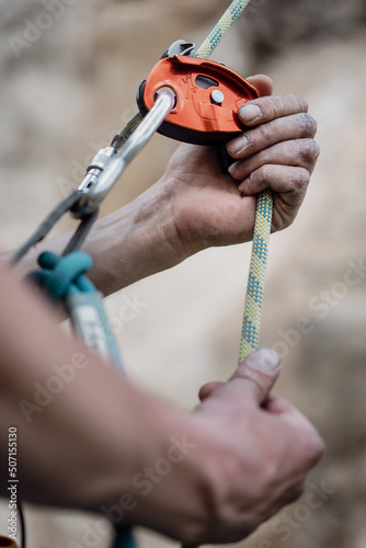 Man's hands operating a rock climbing belaying device