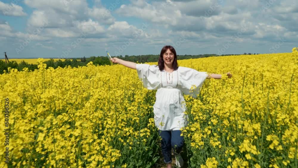 Ukraine, the Lviv region, the young pregnant girl cheerfully runs among rapeseed in a rapeseed field with a flag of Ukraine Ukraine, the Lviv region, the young pregnant girl cheerfully runs among rapeseed in a rapeseed field with a flag of Ukraine