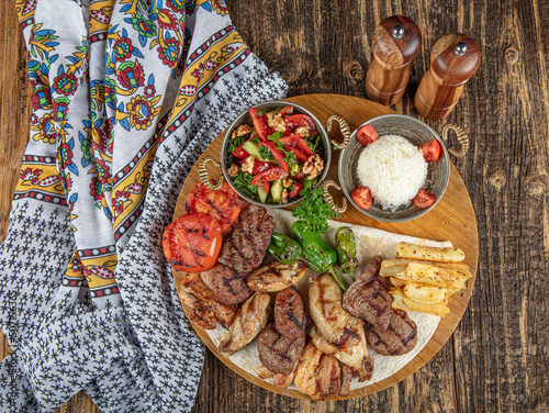 Turkish cuisine, mixed kebab. Meat platter fried on charcoal with spices on a wooden board. Rack of lamb, lamb, kebab, chicken, mushrooms and tomato sauces for meat.