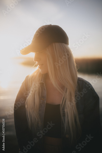 Poważna dziewczyna na tle zachodzącego słońca nad jeziorem