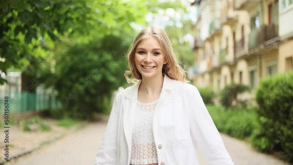 Portrait of attractive smiling woman while walking down the street in the city street and turn around. Beautiful woman looking at the camera outside. Portrait of attractive smiling woman while walking down the street in the city street and turn around. Beautiful woman looking at the camera outside.