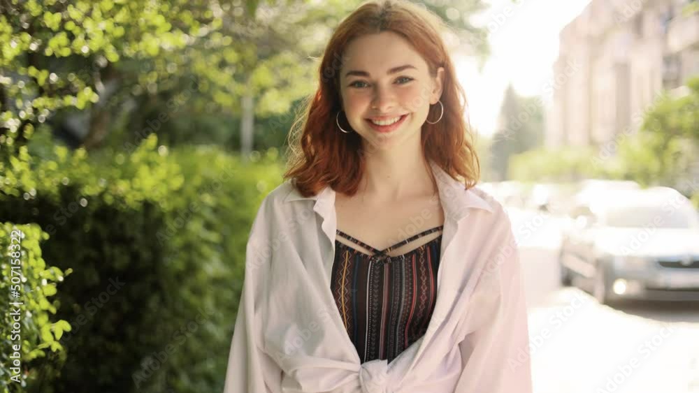 Portrait of attractive red haired woman while walking down the city street and turn around. Beautiful ginger woman looking at the camera outside. Portrait of attractive red haired woman while walking down the city street and turn around. Beautiful ginger woman looking at the camera outside.