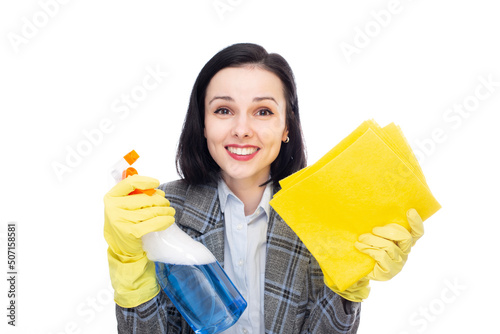 smiling businesswoman in office suit with cleaning gloves holding rags and household chemicals in her hands, white studio background. High quality photo