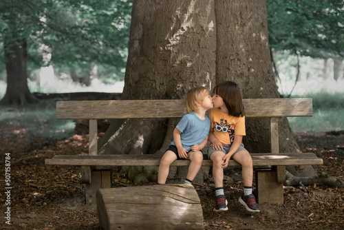Two child kissing each other on the bench