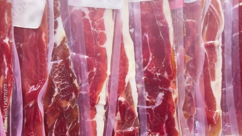 Iberian ham in vacuum plastic packs on a supermarket or grocery window. Closeup  photo