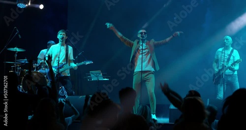 Performance of a pop or rock group, music band on stage. Stage neon light and bright strobe flashes
