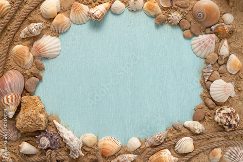 Marine themed frame for text. Blue background with seashells on the sand with empty space.