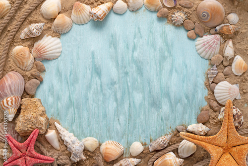Marine themed frame for text. Blue background with seashells and starfish on the sand with empty space.
