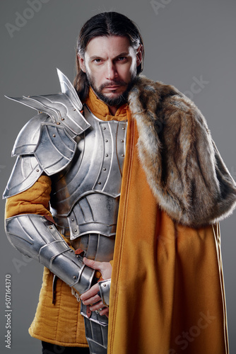 Fototapeta The King. Handsome Medieval knight in armor and yellow cloak.
