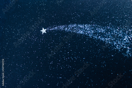 Confetti applique on dark blue glitter of cardboard. Shooting star and stardust. Concept of dream and make a wish. Selective focus, copy space.