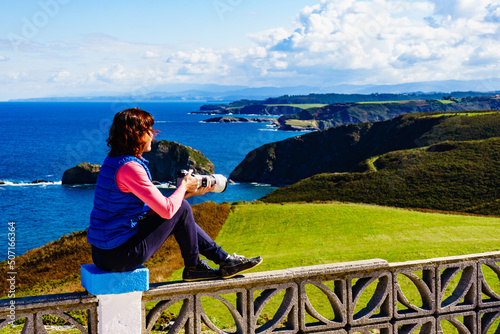 Tourist with camera on Asturias coast, Spain photo