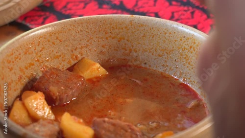 HEVIZ, ZALA, HUNGARY - AUGUST 19, 2018: Eating traditional hungarian bogracs soup in Heviz, Hungary. 4K, Handheld, Close-up photo