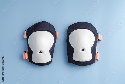 Top view of roller skates protective gear set - knee pads in pink colors. Blue background flat lay  photo