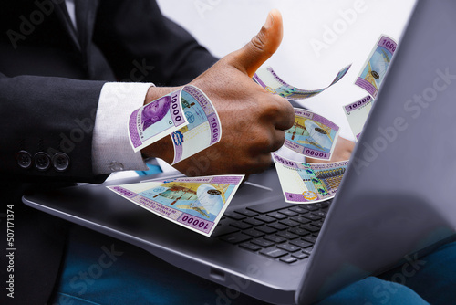 Central African cfa franc notes coming out of laptop with Business man giving thumbs up, Financial concept. Make money on the Internet, working with a laptop photo