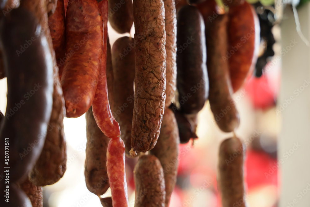 Fototapeta premium Swojska tradycyjna kiełbasa wieprzowa wisi na haku. 