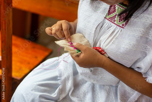 Close up of a Mexican indigenous woman embroidering traditional patters 