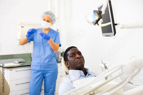 Adult African American sitting in chair in modern dental clinic  waiting for checkup or treatments