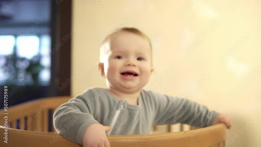 Happy emotion child jumps and dabbles in the crib at home during the day in pajamas, gestures and waves his hands. Cozy family atmosphere. Portrait of a boy smiles and emotion plays in cradle bedroom. Happy emotion child jumps and dabbles in the crib at home during the day in pajamas, gestures and waves his hands. Cozy family atmosphere. Portrait of a boy smiles and emotion plays in cradle bedroom.