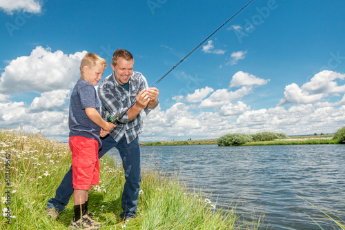 A father and son fishing together on a river bank on a beautiful summer day.