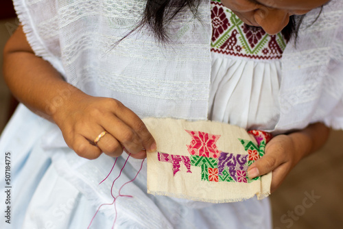 Close up of a woman embroidering traditional Mexican patterns from puebla