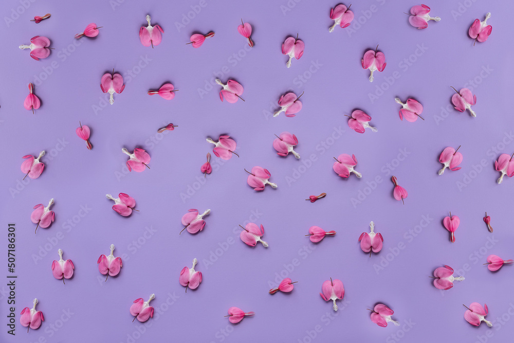Naklejka premium Floral background. Delicate pink flowers in the shape of hearts on a lilac background. Top view.