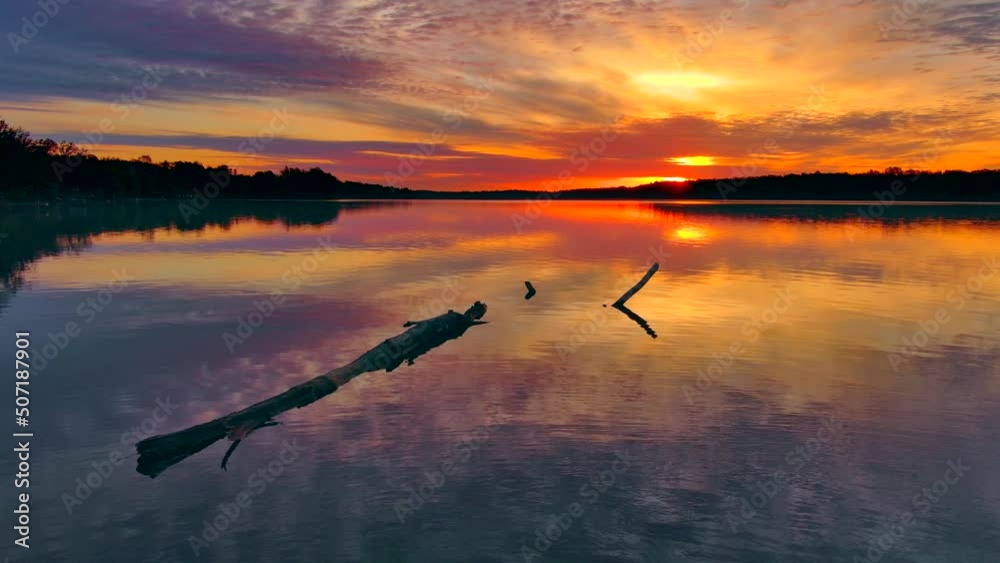 Spectacular colorful clouds, red sky reflected in tranquil lake at dawn.
