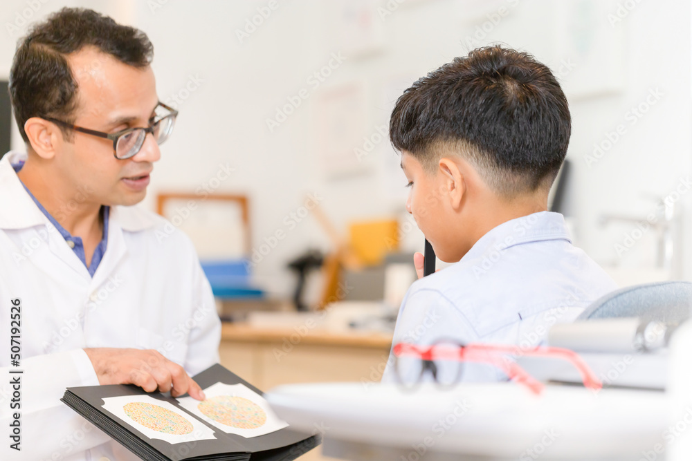 Obraz premium Boy doing eye test checking examination with optometrist in optical shop, Indian-thai boy in optics store