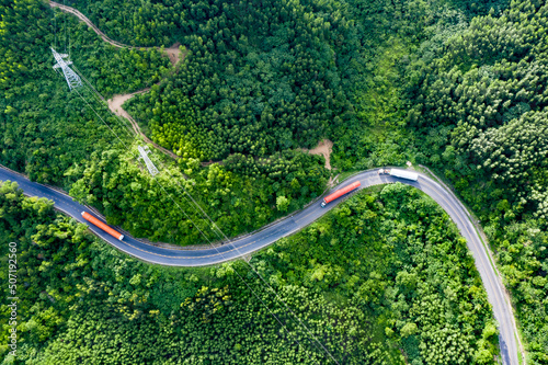 Transporting wind turbine propeller through curvy jungle road. Clean alternative energy to reduce global warming and climate change for sustainable growth.