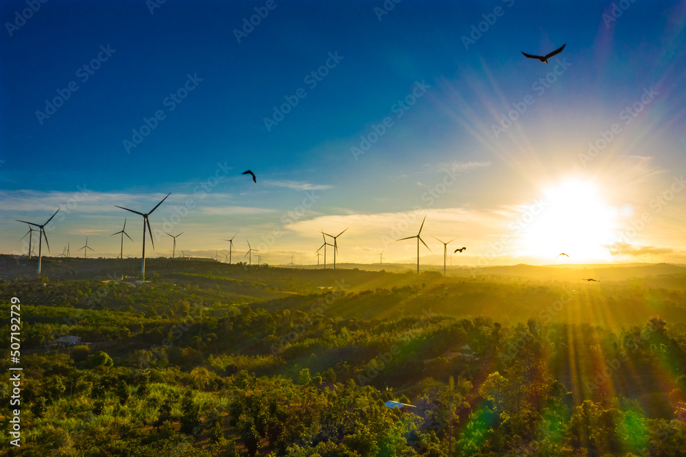 Wind turbines in a big green field at sunset generating electricity. Clean alternative energy to reduce global warming and climate change for sustainable growth. Wind turbines in a big green field at sunset generating electricity. Clean alternative energy to reduce global warming and climate change for sustainable growth.