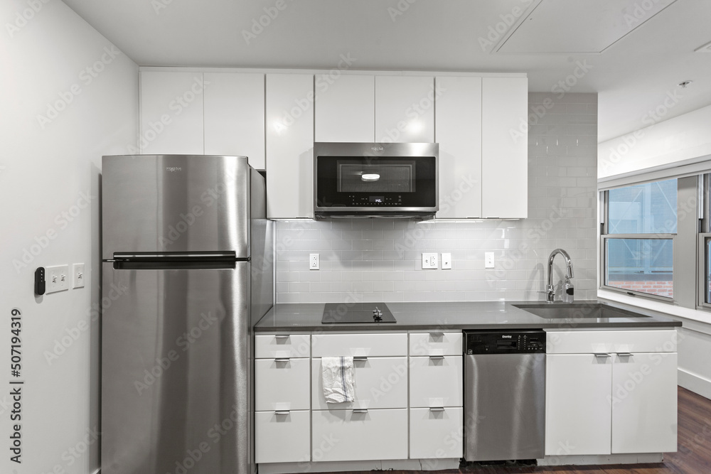 White apartment kitchen with black counter tops and white cabinets in city apartment White apartment kitchen with black counter tops and white cabinets in city apartment