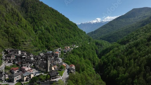 A dynamic rearward moving aerial footage of the towns of Villadossola, Domodossola, and Simplon pass. These towns are surrounded by beautiful mountains of the Italian Piemont region in Southern Alps.