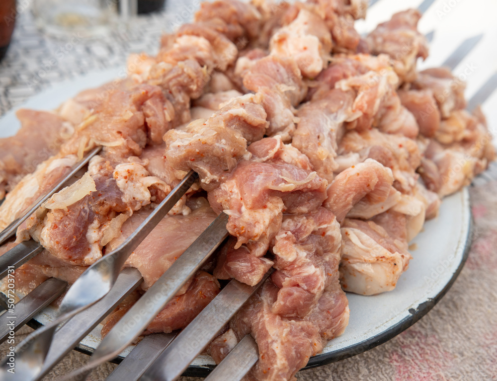 Pieces of raw meat on metal skewers in a plate. Pieces of raw meat on metal skewers in a plate.