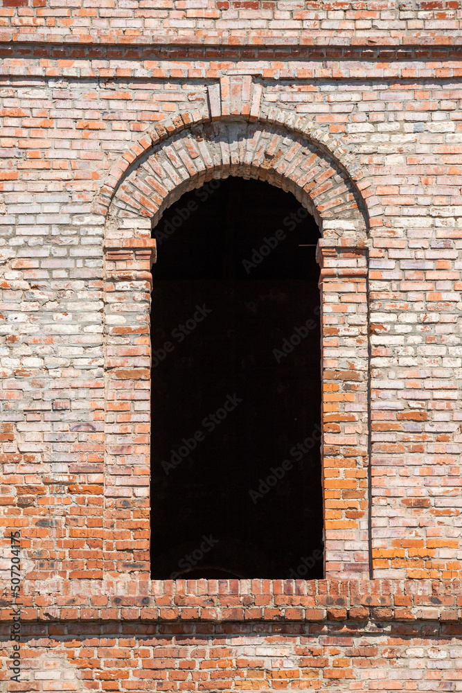 Broken semicircular windows in an old brick building.