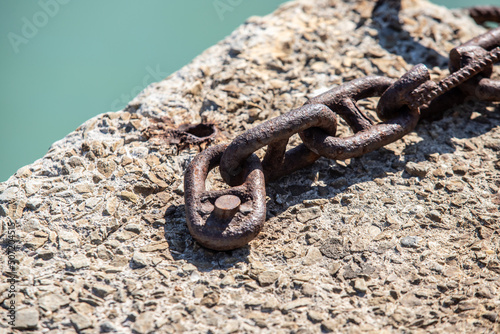 A rusty metal chain, a pole on the beach. © Prikhodko