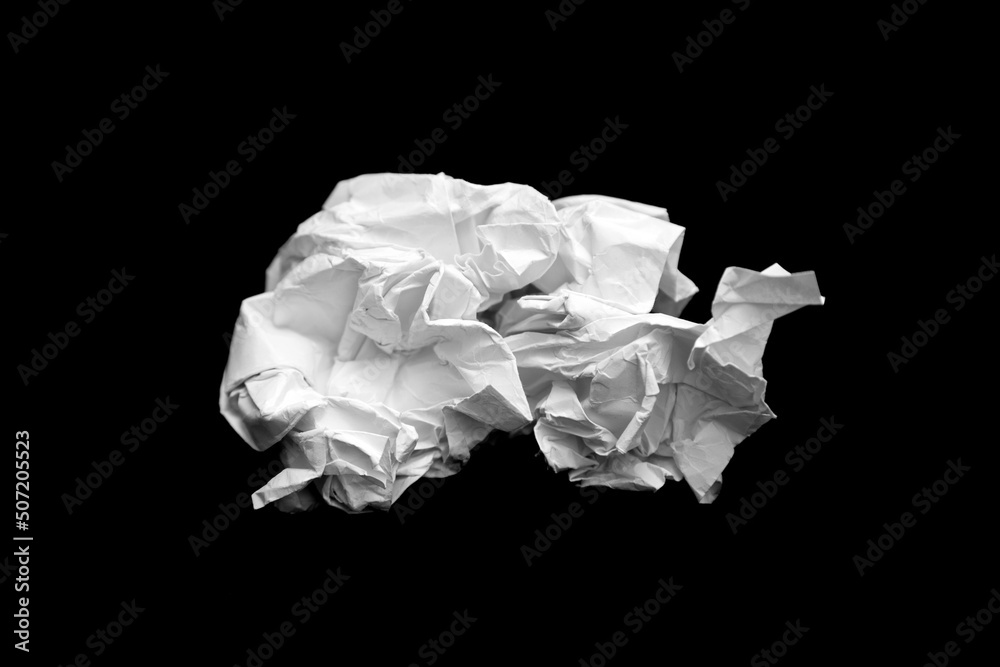 A piece of crumpled white paper on a black background. A piece of crumpled white paper on a black background.