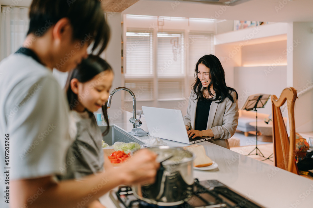 仕事をする母と食事の準備をする父と娘 仕事をする母と食事の準備をする父と娘