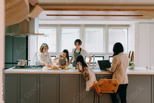 キッチンで食事の準備をする家族と働く母親