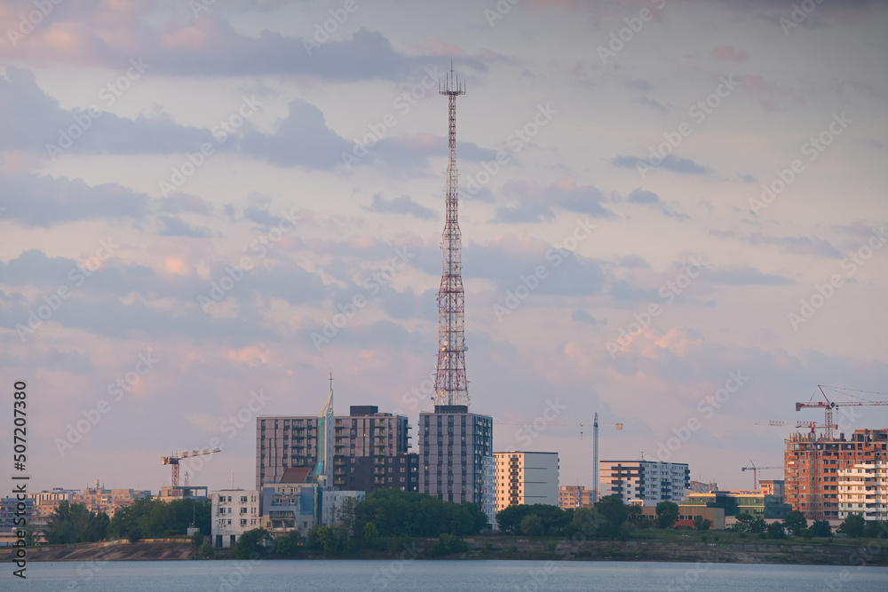 Cityscape in Bucharest from Morii Lake (Lacul Morii) photographed during a summer sunrise with view to the main communication scaffolding tower.