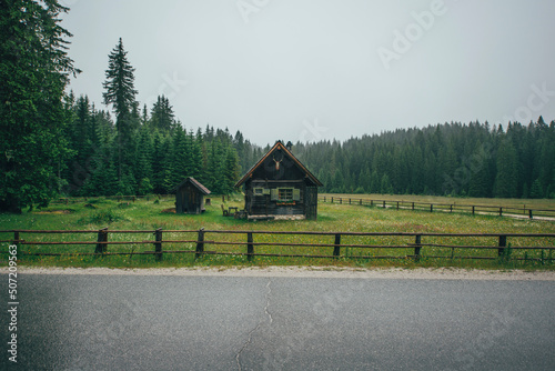 Autumn view of the valley and wooden cottages below the dark and foggy mountains.
 photo