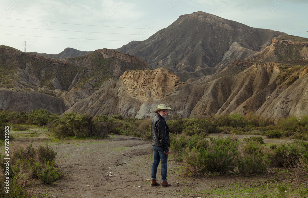 Rear view of adult man in cowboy hat in oasis of desert. Almeria, Spain